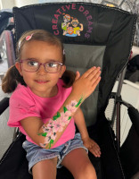 Girl with glasses and pink flowers painted on her arm